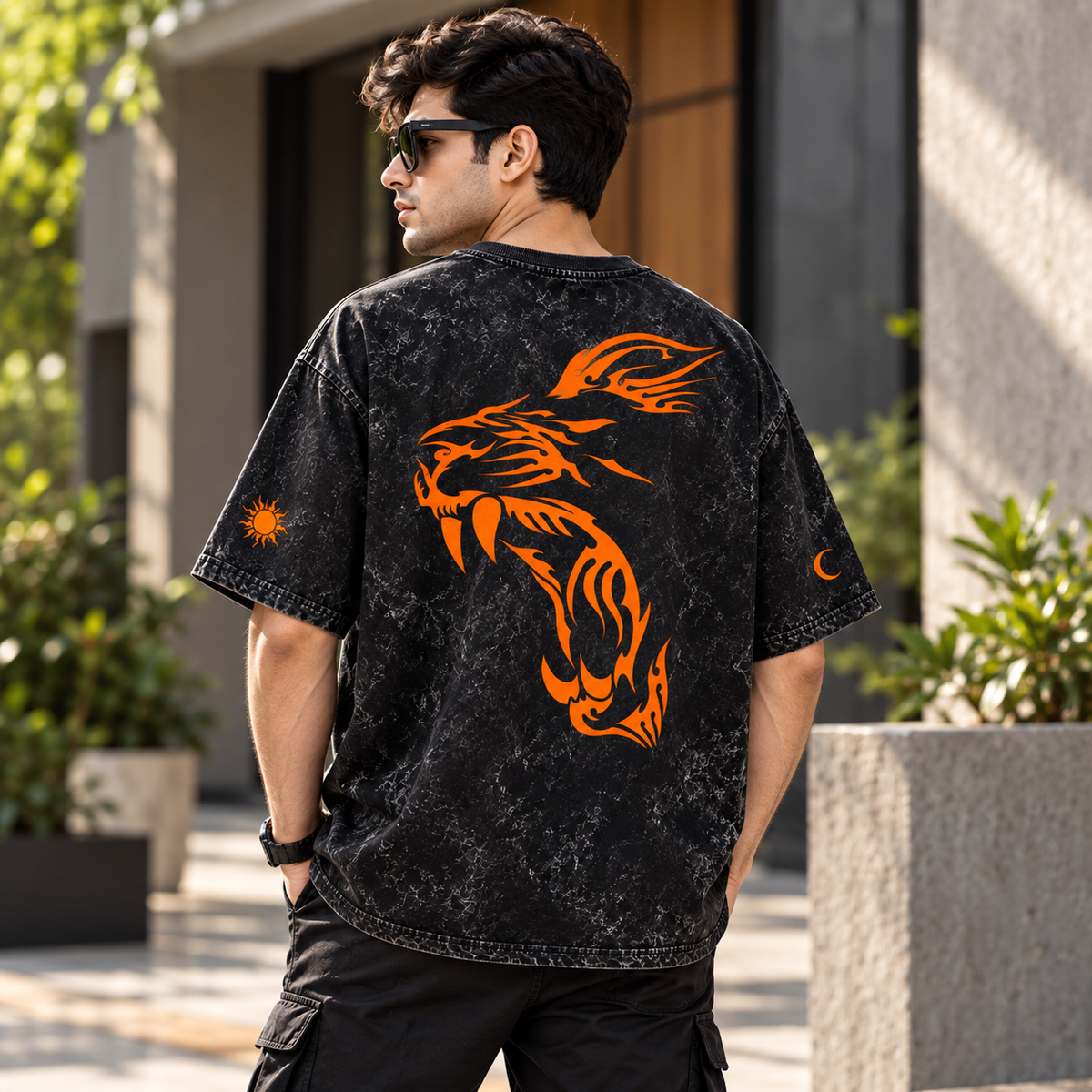 A man wearing a black acid-wash t-shirt with a large orange tiger graphic on the back, photographed from behind in an outdoor setting.
